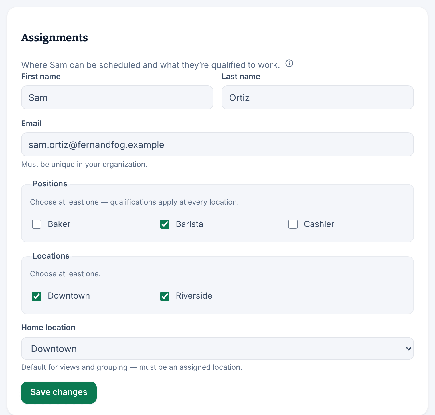 The Assignments panel for Sam Ortiz, with Barista ticked under Positions, Downtown and Riverside ticked under Locations, Downtown as the home location, and the Save changes button.